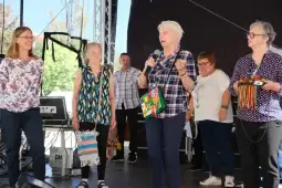 Kobiety na scenie podczas wystąpienia, jedna z nich trzyma mikrofon.