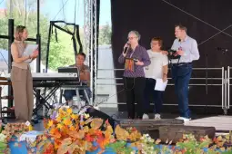 Grupa osób na scenie podczas wystąpienia, z instrumentami muzycznymi i notatkami.