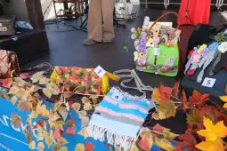 Torby ręcznie robione, ozdobione kwiatami i frędzlami, na tle sceny festiwalowej.
