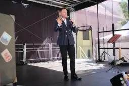 Mężczyzna w marynarce przemawia do publiczności na scenie.