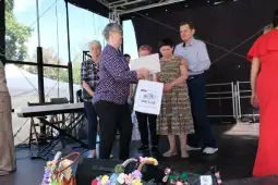 Wręczenie nagrody na scenie podczas wydarzenia, uczestnicy w różnorodnych strojach.