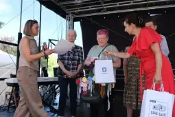 Wręczenie nagród podczas wydarzenia, uczestnicy z torbami i rękodziełem.