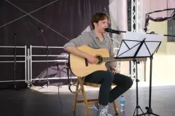 Mężczyzna gra na gitarze i śpiewa na scenie.