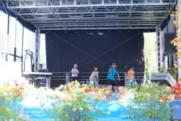 Muzycy na scenie podczas występu, instrumenty muzyczne i dekoracje w tle.
