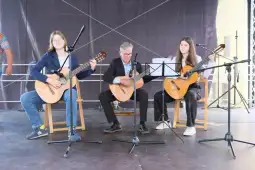 Trzech muzyków grających na gitarach na scenie.