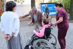 Osoba na wózku inwalidzkim rozmawia z mężczyzną, obok stoją dwie kobiety.