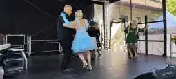 Para tańcząca w kolorowych strojach na scenie podczas wydarzenia kulturalnego.