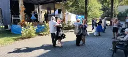 Seniorzy tańczą na świeżym powietrzu podczas wydarzenia kulturalnego.