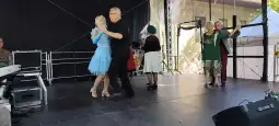 Para tańcząca na scenie, w tle inne osoby oraz instrumenty muzyczne.