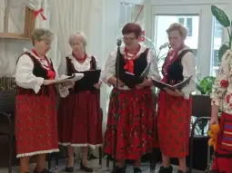 Cztery kobiety w tradycyjnych strojach ludowych śpiewają przy mikrofonie.