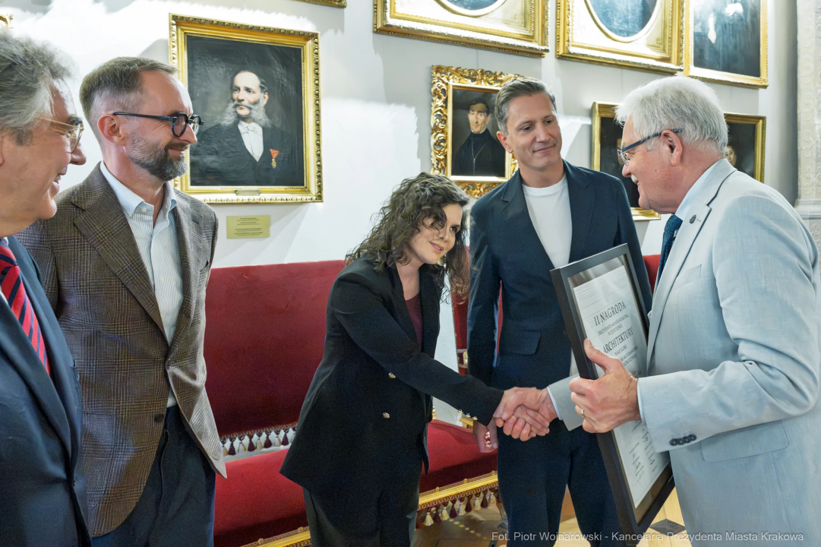 Wręczenie nagrody w towarzystwie kilku osób w eleganckim wnętrzu.  Autor: Piotr Wojnarowski