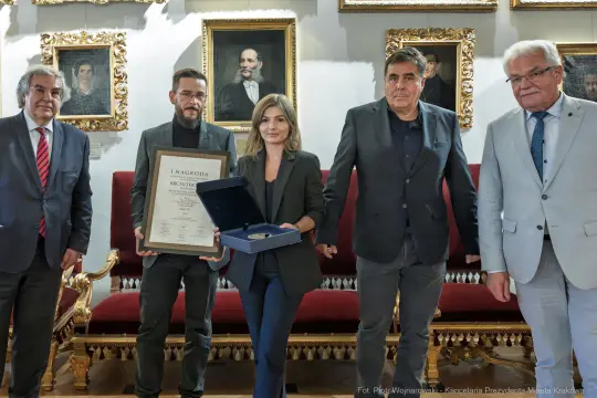 Wręczenie nagrody architektonicznej w eleganckim otoczeniu z pięcioma osobami.