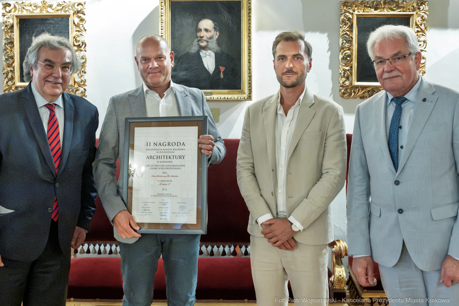Czterech mężczyzn z dyplomem nagrody architektonicznej w eleganckim wnętrzu.  Autor: Piotr Wojnarowski