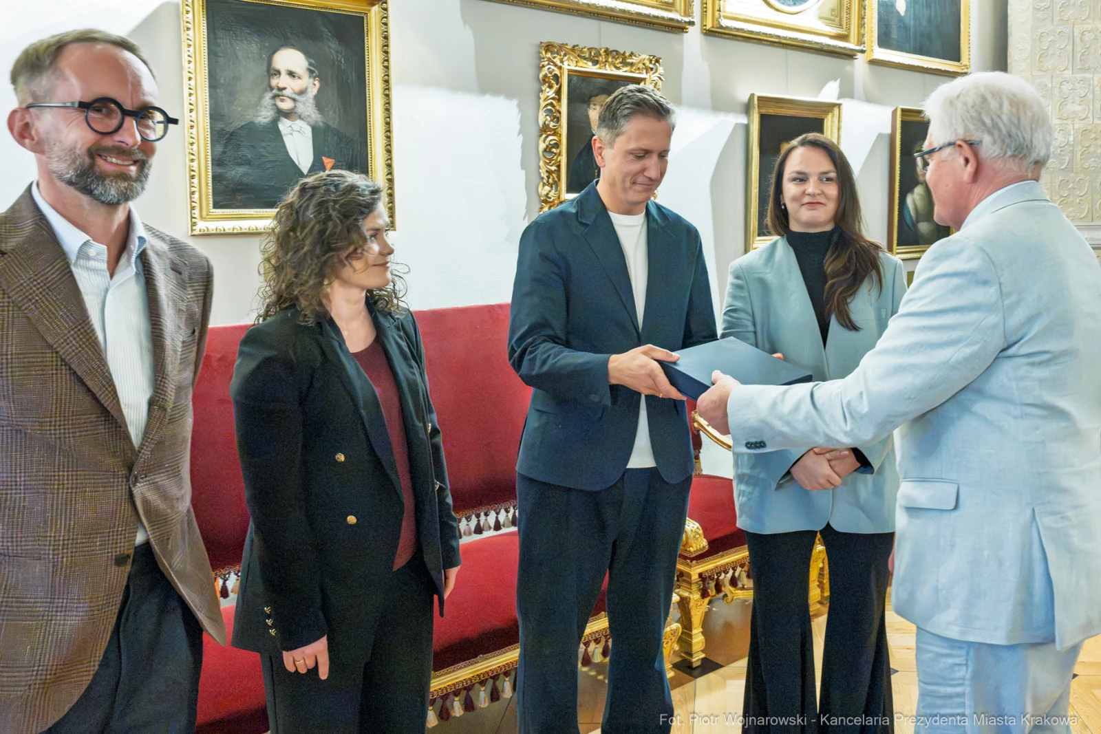 Wręczenie nagrody w uroczystej atmosferze, cztery osoby w formalnych strojach.  Autor: Piotr Wojnarowski