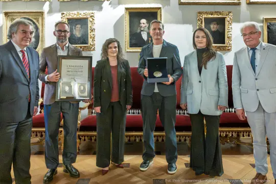 Wręczenie nagrody architektonicznej grupie laureatów w eleganckim wnętrzu.