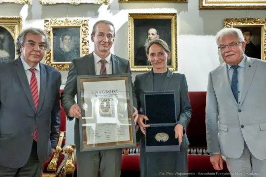 Wręczenie nagrody w obecności czterech osób, w tym laureatki, z dyplomem i medalem.
