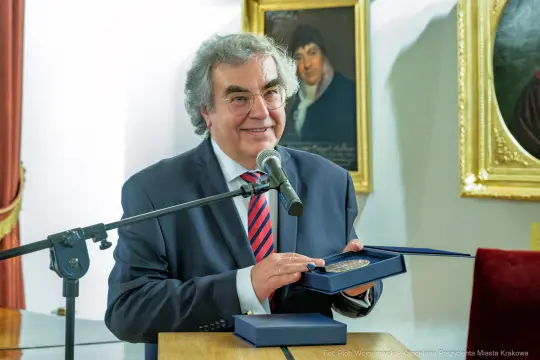 Mężczyzna trzyma medal i przemawia do zgromadzonej publiczności.
