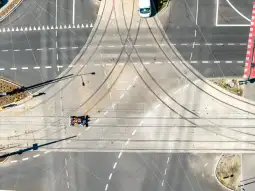 Widok na skrzyżowanie ulic z torami tramwajowymi i pojazdem na drodze.