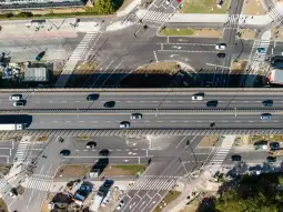 Widok na skrzyżowanie dróg z ruchem samochodowym i budową w tle.