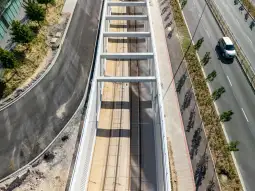 Widok na torowisko tramwajowe z otoczeniem drogowym i zielenią.