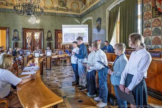 Grupa dzieci prezentuje projekt w sali obrad.