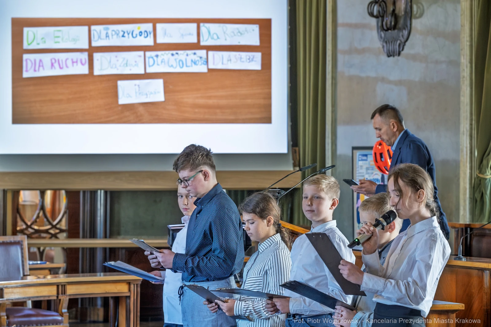 Dzieci prezentujące teksty na scenie podczas wydarzenia w sali.  Autor: Piotr Wojnarowski