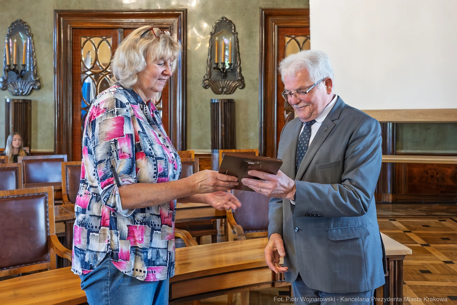 Wręczenie nagrody przez mężczyznę kobiecie w eleganckim wnętrzu sali.  Autor: Piotr Wojnarowski