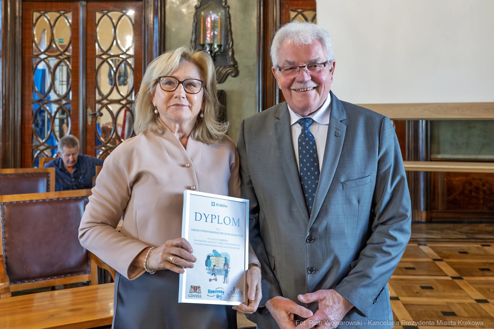 Dwójka ludzi trzyma dyplom w eleganckim wnętrzu.  Autor: Piotr Wojnarowski