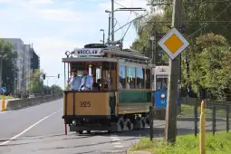 Tramwaj wrocławski na ulicy, z widocznymi pasażerami i oznakowaniem kierunkowym.