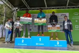 Zawodnicy na podium z nagrodami w trakcie zawodów sportowych w Krakowie.