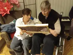 Kobieta w wózku inwalidzkim i druga osoba wspólnie oglądają obraz.