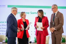 Cztery osoby w formalnych strojach podczas wręczenia certyfikatów.