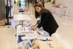Kobieta układa materiały promocyjne na stole w przestrzeni konferencyjnej.