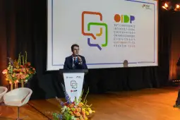 Mężczyzna przemawia z mównicy na konferencji OIDP w Krakowie, w tle logo wydarzenia.