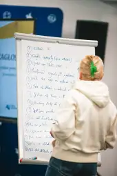 Kobieta pisząca na tablicy flipchart z wypunktowanymi zagadnieniami.