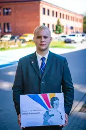 Mężczyzna w garniturze trzyma plakat z hasłem o głosowaniu.