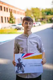 Młody mężczyzna trzyma plakat z hasłem o budzeniu pasji i zachęceniu do działania.