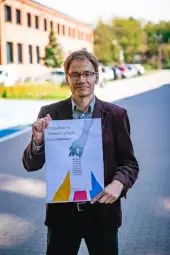 Mężczyzna trzyma plakat z hasłem o przyszłości i zachęceniem do głosowania.