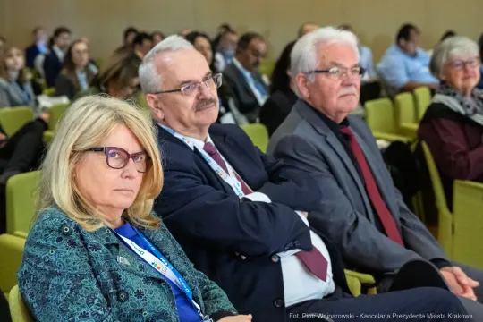 Trzy osoby siedzące na konferencji, skupione na prelekcji.