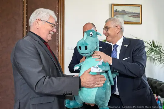 Mężczyźni wręczają sobie pluszowego smoka.