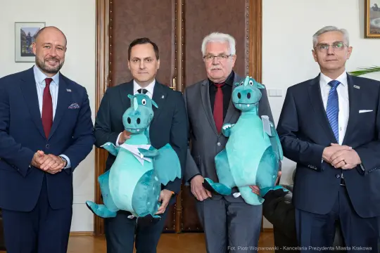 Czterech mężczyzn trzymających pluszowe smoki w biurze.