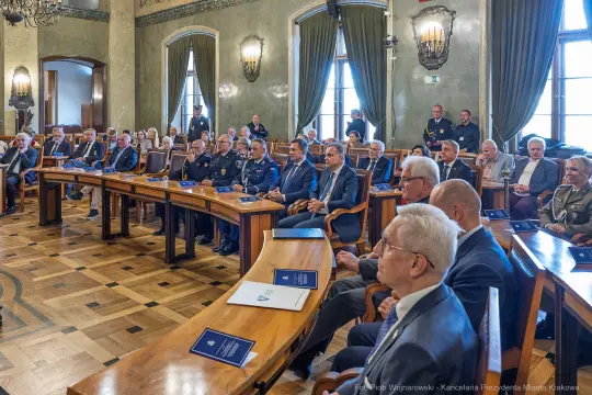 Spotkanie w sali obrad z uczestnikami w garniturach i mundurach.