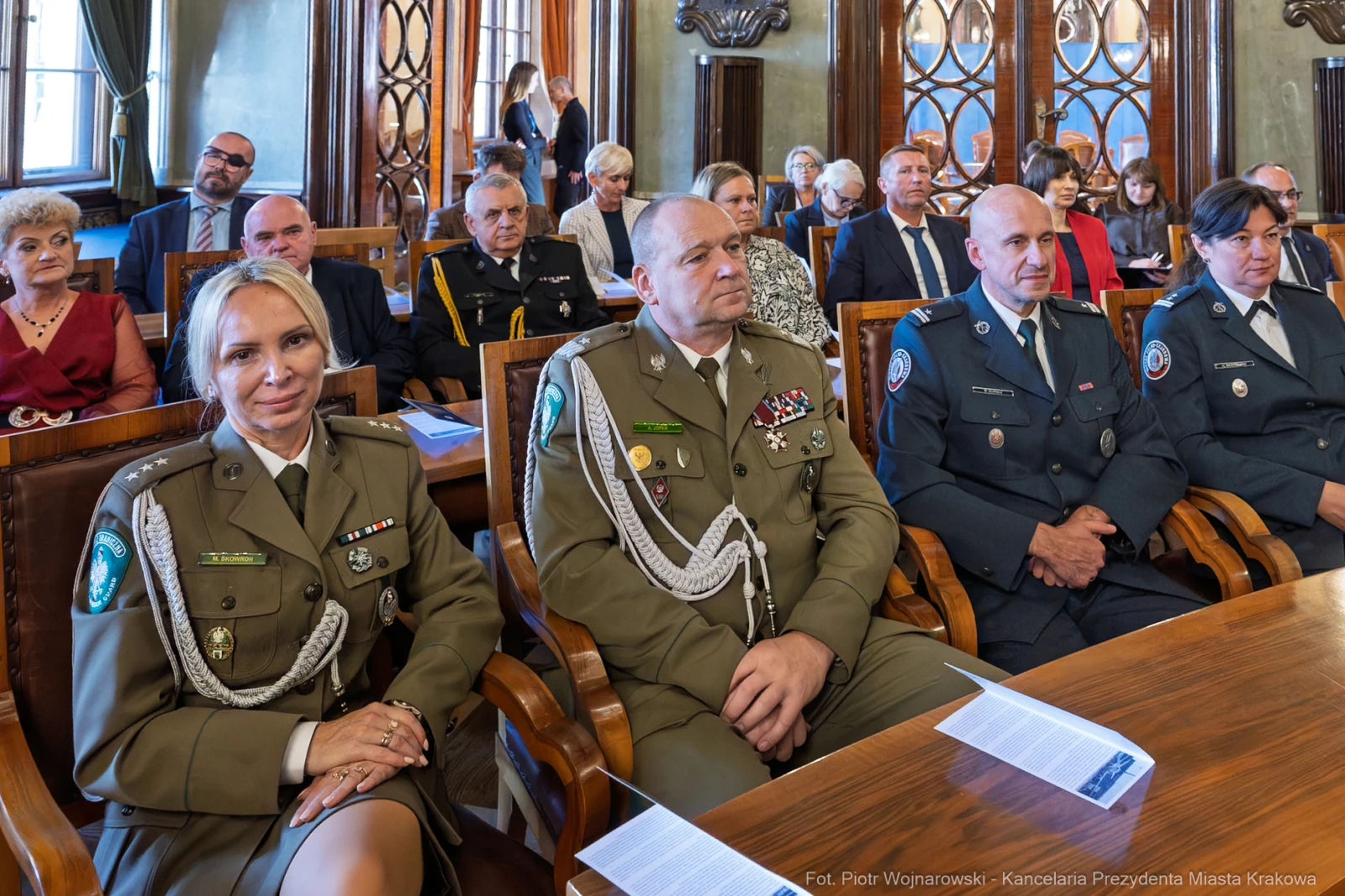 Grupa osób w mundurach i garniturach siedząca w sali podczas uroczystości.  Autor: Piotr Wojnarowski