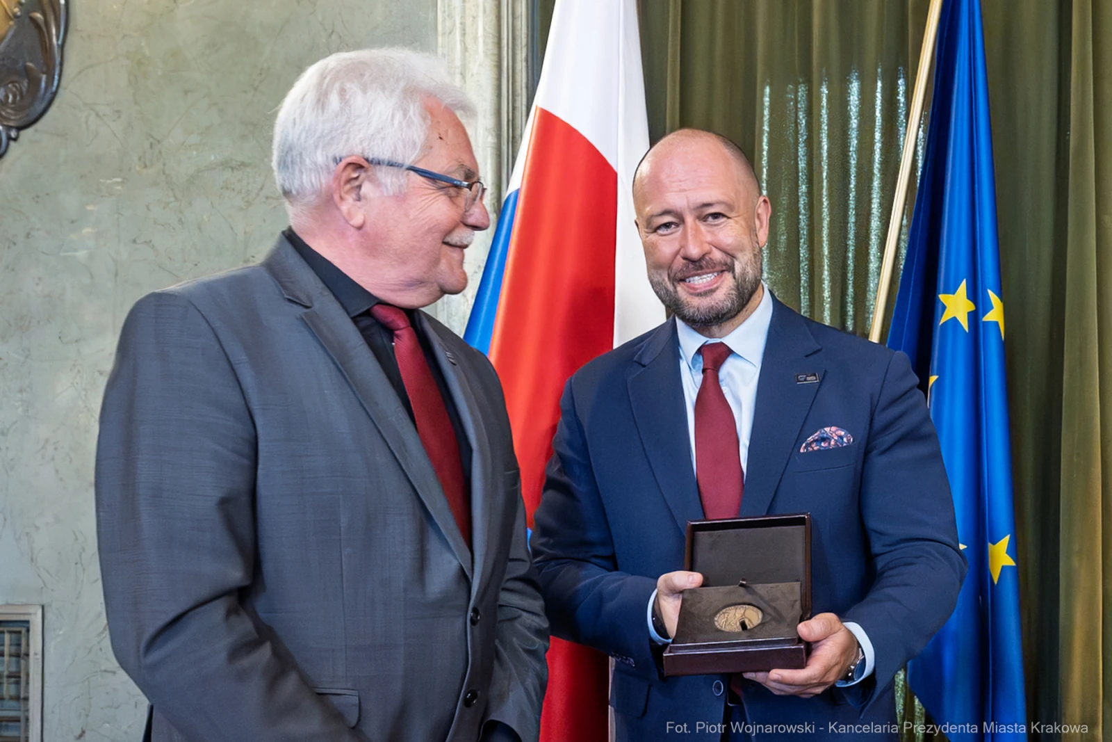 Wręczenie medalu w uroczystej atmosferze, dwóch mężczyzn w garniturach.  Autor: Piotr Wojnarowski
