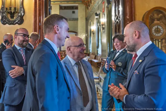 Spotkanie kilku mężczyzn i kobiet w eleganckich strojach, rozmowy w stylowym wnętrzu.