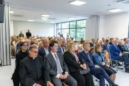 Grupa ludzi siedzących w sali podczas wydarzenia.