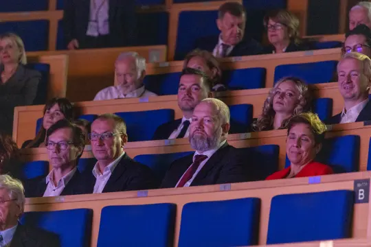 Grupa ludzi siedzących na widowni w sali konferencyjnej.