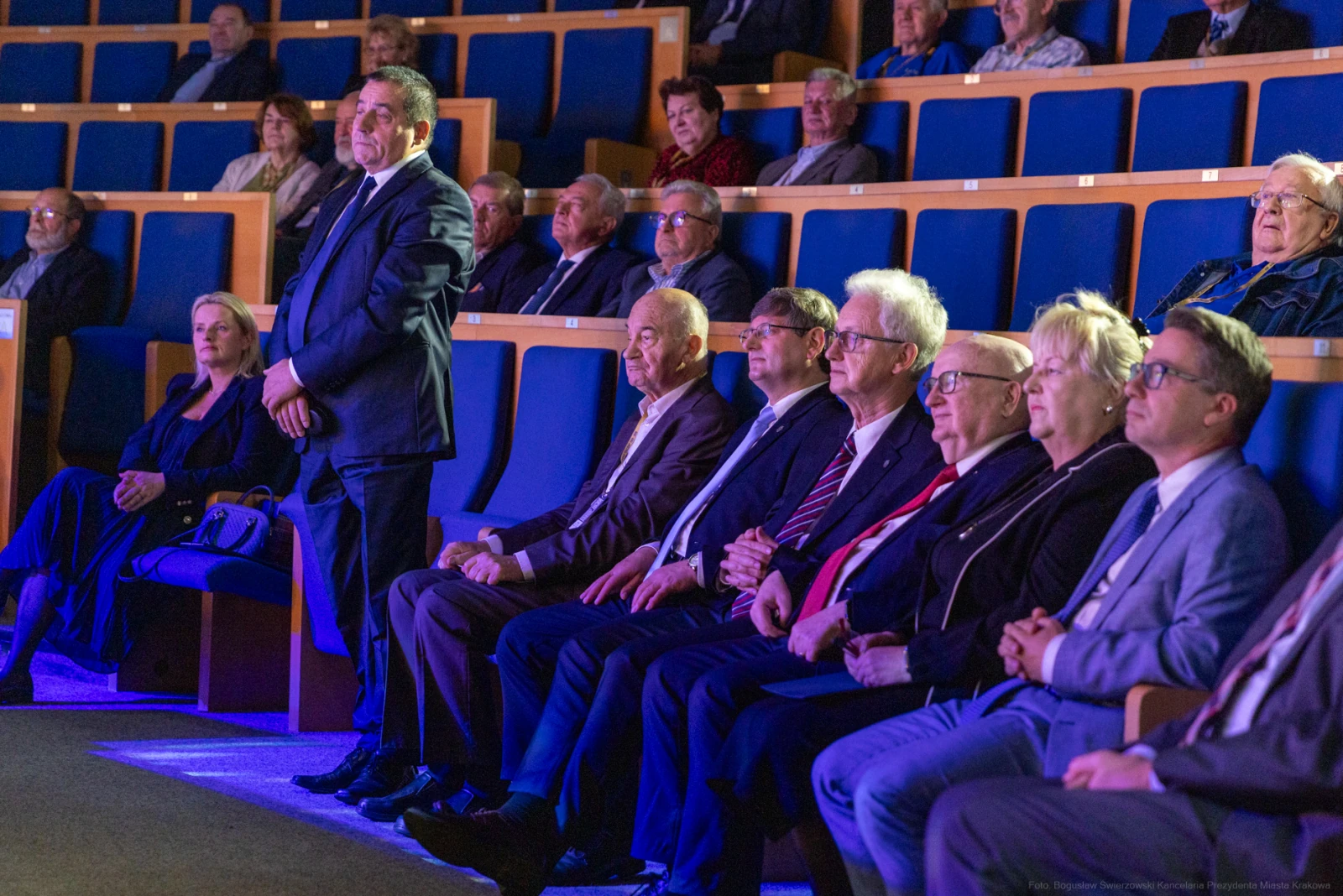 Grupa osób siedzących na widowni w sali teatralnej, z widocznymi reflektorami i oświetleniem.  Autor: Bogusław Świerzowski