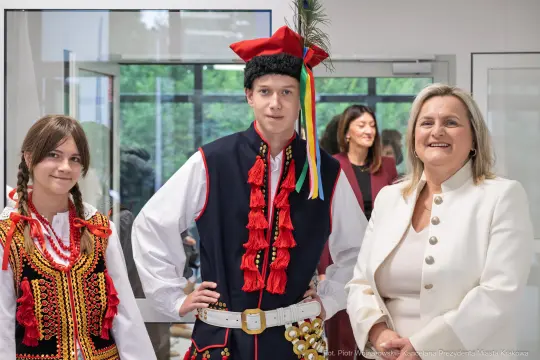 Młodzież w tradycyjnych strojach ludowych z uśmiechami.
