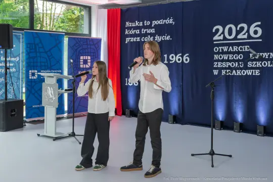 Dwoje młodych wykonawców śpiewa na scenie podczas wydarzenia szkolnego.